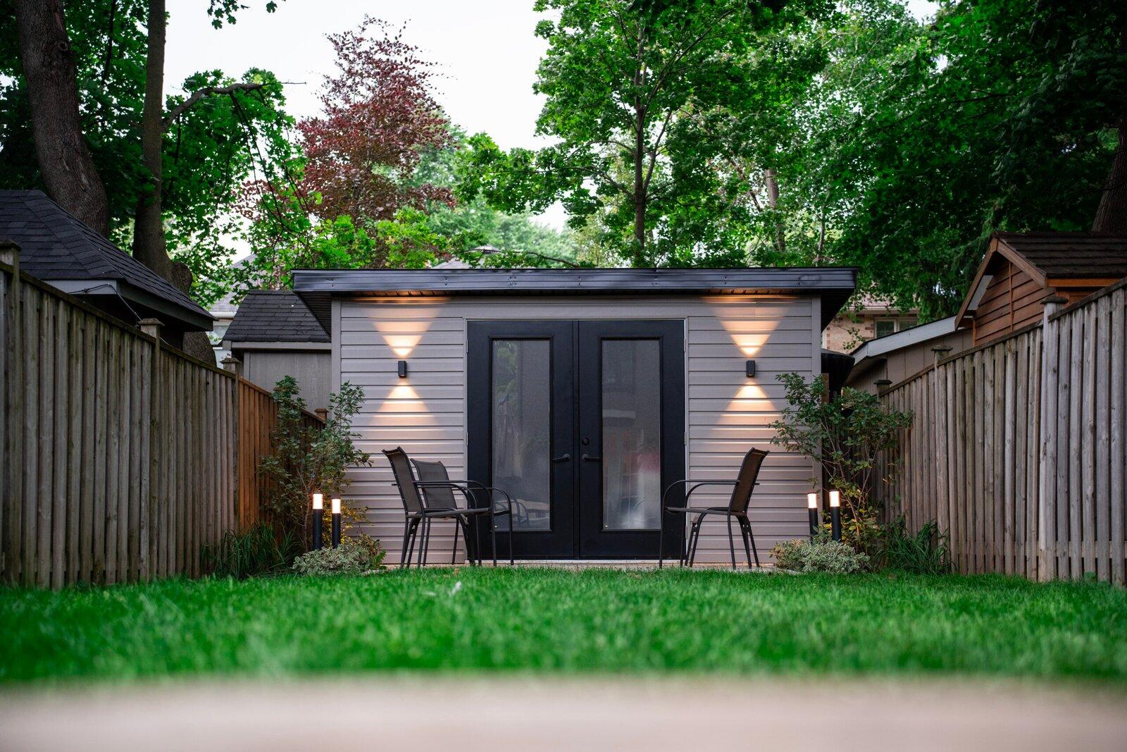 Garden studio at dusk with wall sconces and bollard lighting